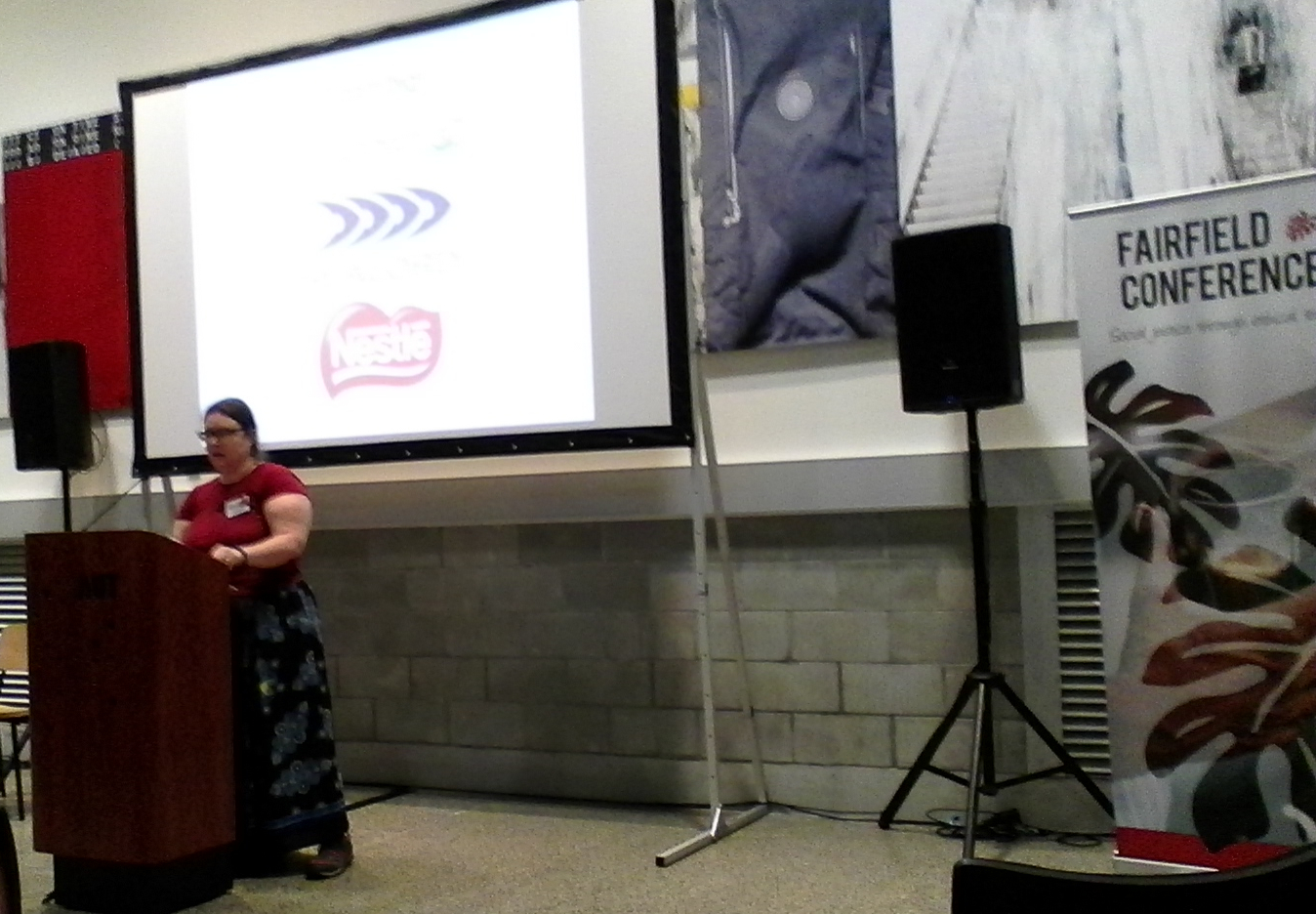 Heather in front of a podium. Behind is a screen with Countdown, Sealord and Nestle logos.